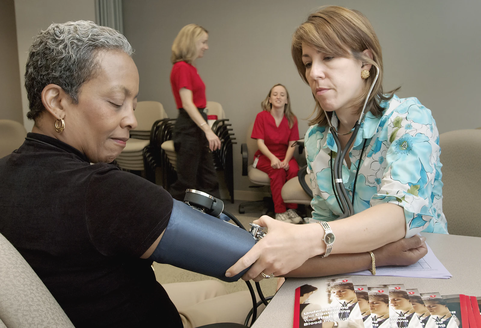 A nurse taking a patient's blood pressure during a clinic intake, the kind of routine encounter where Protected Health Information (PHI) is created and must be handled under HIPAA.